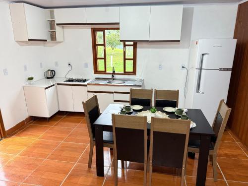a kitchen with a table with chairs and a refrigerator at Cabanas Belvedere in Lauro Müller
