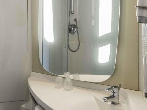 a bathroom with a sink with a large mirror at Ibis Salamanca in Salamanca