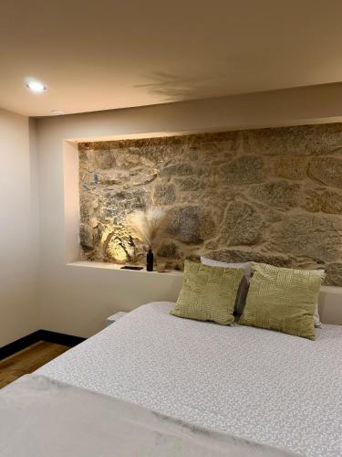 a bedroom with a stone wall behind a bed at Fagundes Village in Valença