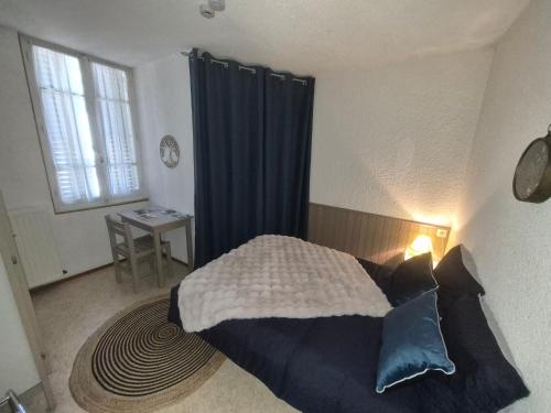 a bedroom with a bed with blue curtains and a table at Auberge du sichon in Ferrières-sur-Sichon