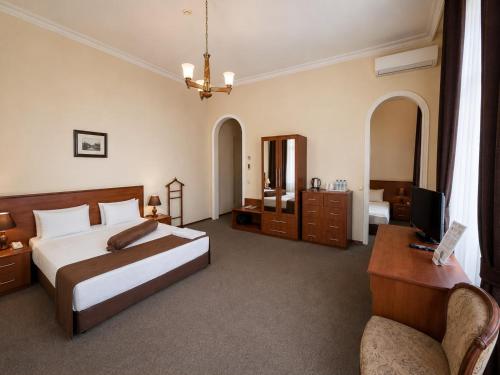 a bedroom with a bed and a desk and a television at Azcot Nizami Hotel in Baku
