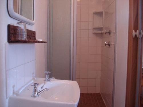 a bathroom with a sink and a shower with a mirror at Bay Cove Inn in Jeffreys Bay