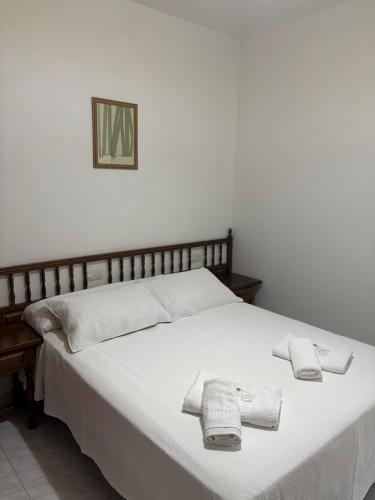a white bed with two towels on top of it at Pensión Las Arenas in Vilagarcia de Arousa