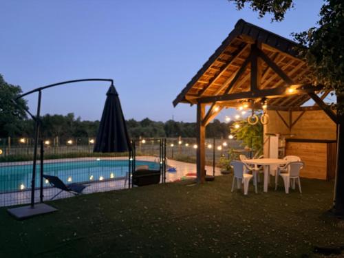 a gazebo with a table and chairs next to a pool at Gite d'Aimelles in Billezois