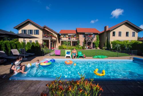 una familia jugando en una piscina en una casa en Villa Mare Apartamenty, en Grzybowo