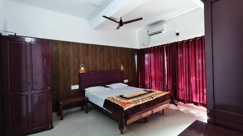 a bedroom with a bed and red curtains at Udaya Hotel in Kovalam