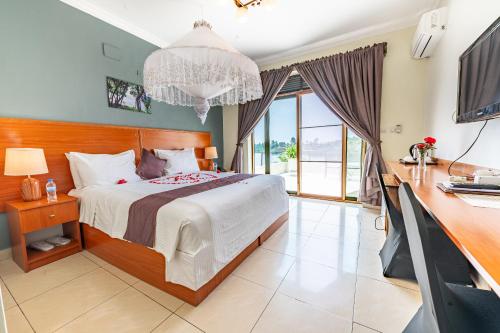 a bedroom with a bed and a desk and a television at Moriah Hill Resort in Kibuye