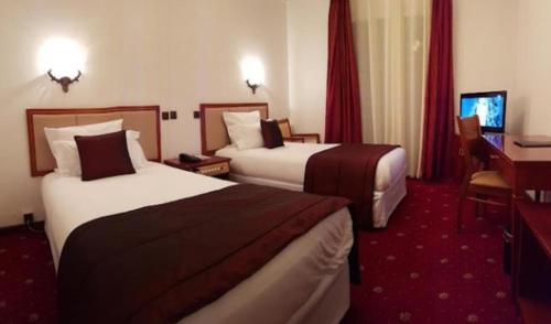 a hotel room with two beds and a desk at Chaine ELDJAZAIR by HTT in Alger