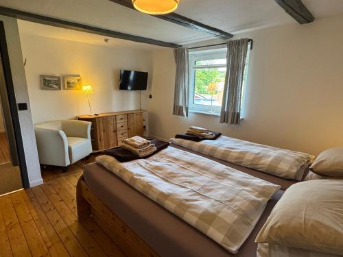 a room with two beds and a chair and a window at Ferienwohnung Sonnentau 1 in Holzminden