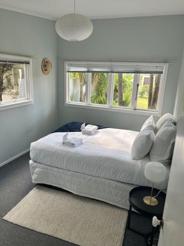 a bedroom with a large white bed and two windows at Oneroa Manuka Residence in Waiheke Island