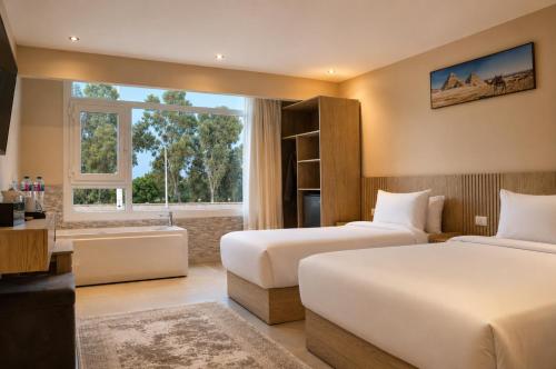 a hotel room with two beds and a window at Dar Pyramids Boutique in Cairo