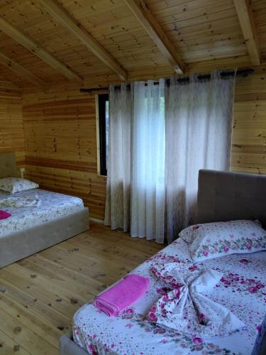 a bedroom with two beds in a wooden cabin at Krahina e Shllakut in Koman