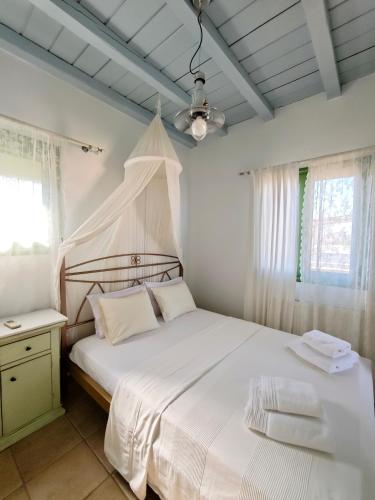 a bedroom with a white bed with a canopy at MONI apartment in Perdika