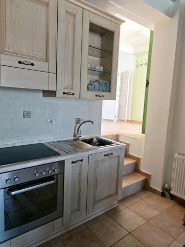 a kitchen with wooden cabinets and a sink and stairs at MONI apartment in Perdika