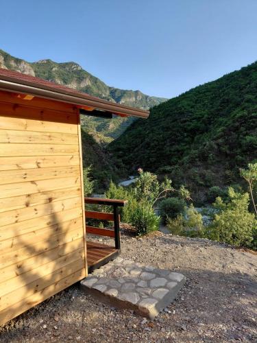a wooden building with a bench next to a mountain at Krahina e Shllakut in Koman