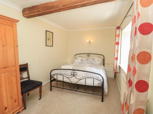 a small bedroom with a bed and a chair at Byre Cottage 3 in Pulborough