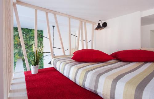 a bedroom with a bed with red pillows and a red rug at Giedres Old Town Apartments in Kaunas
