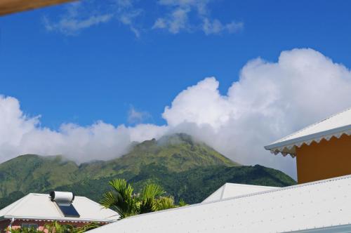 a view of a mountain with clouds in the sky at Hôtel Village Pomme Cannelle 3 étoiles in Le Prêcheur