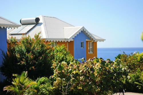 a house with the ocean in the background at Hôtel Village Pomme Cannelle 3 étoiles in Le Prêcheur