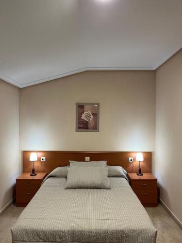 a bedroom with a large bed with two lamps on the sides at Pension As Termas in Bubaces