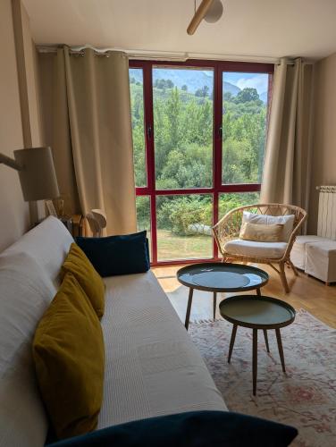 a living room with a couch and tables and a window at Apartamento LLAR DEL CARES in Arenas de Cabrales