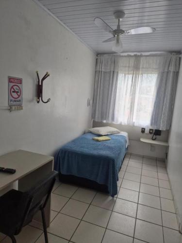 a small bedroom with a bed and a window at Hotel Eduardo's in Rio do Sul