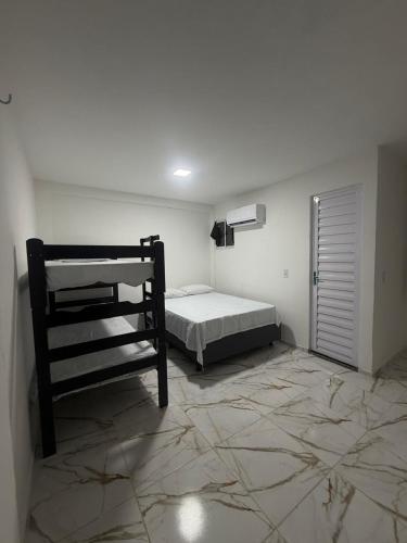 a bedroom with a bed in a white room at Pousada Sol Brasil in Fortaleza