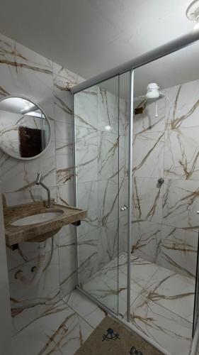 a bathroom with a shower with a sink and a mirror at Pousada Sol Brasil in Fortaleza