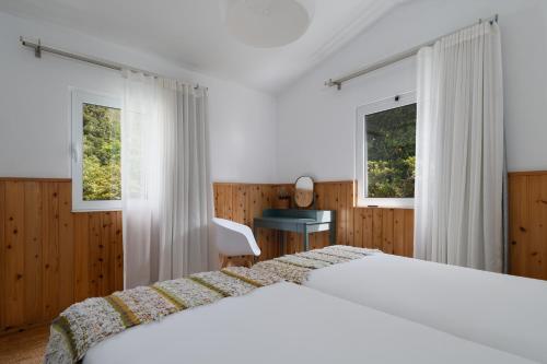 a bedroom with two beds and two windows at Furnas Lake Forest Living in Furnas