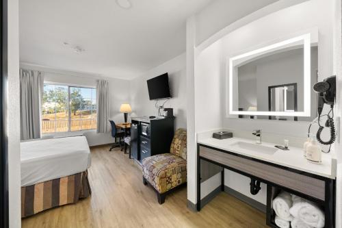 a hotel room with a bed a sink and a mirror at Ramada by Wyndham Ontario Airport & Convention Center in Ontario