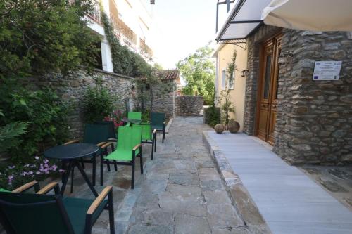 a patio with green chairs and tables and a building at Ξενώνας Λελέκι in Ayiá