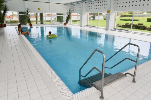 a large swimming pool with two people in the water at See- & Bergblick Oberteuringen 58 mit beheiztem Indoor-Pool in Oberteuringen