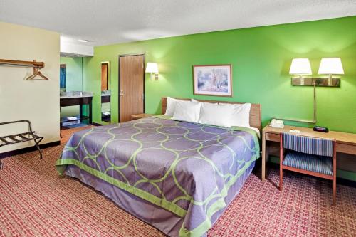 ein Hotelzimmer mit einem Bett und einem Schreibtisch in der Unterkunft Super 8 by Wyndham Romeoville Bolingbrook in Romeoville