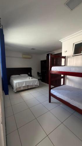 a bedroom with two beds and a tiled floor at Hotel Sol Brasil in Fortaleza
