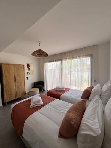 a bedroom with two beds and a large window at Villa Lagoon in Carnon-Plage