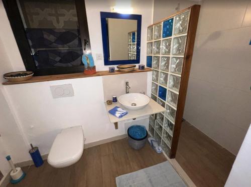 a bathroom with a sink and a toilet and a mirror at Maison Sahel - African Art & Coastal Serenity in Dakar
