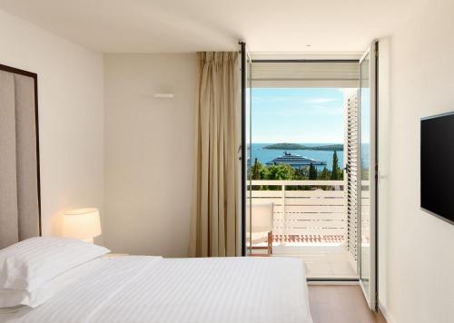 a bedroom with a white bed and a balcony at Amfora Hvar Grand Beach Resort in Hvar