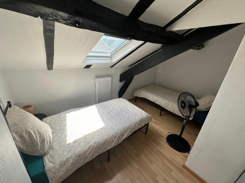 a attic room with two beds and a window at Duplex au cœur de la Bastide in Villefranche-de-Rouergue