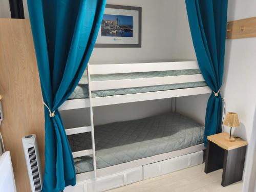 a bedroom with two bunk beds with blue curtains at Notre location au Barcarès in Le Barcarès