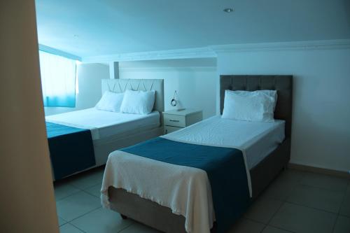 two beds in a room with a blue light at Hakan Pension in Merdivenlikuyu
