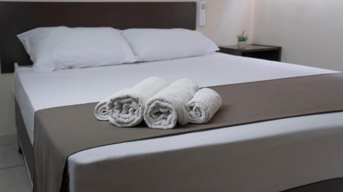 a bedroom with a bed with towels on it at Dom Hotel in Maringá