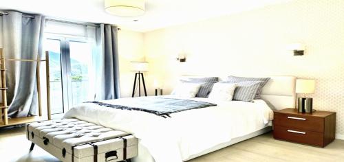 a white bedroom with a large bed and a window at Maisonn La Turbie - Privateee pool in La Turbie