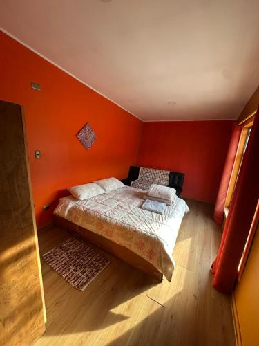 a small bedroom with orange walls and a bed at La Alea Malalcahuello in Malalcahuello