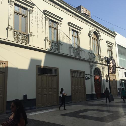 a woman walking in front of a white building at Best place in Plaza Mayor Lima, Pizarro building in Lima