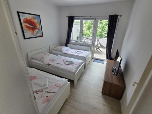 two beds in a room with a window at Ferdimesse Apartments in Cologne