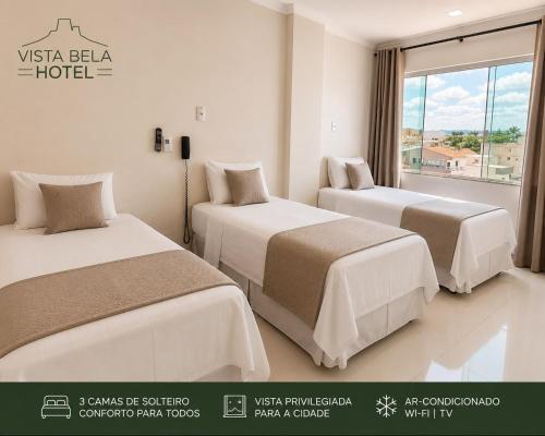 a hotel room with two beds and a window at Hotel Vista Bela in Itamaraju