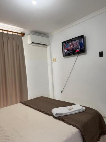 a bedroom with a bed with a tv on the wall at Araújo Hotel in Itaberaba