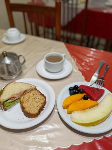 a table with two plates of food and a sandwich and fruit at Araújo Hotel in Itaberaba