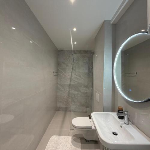 a white bathroom with a sink and a mirror at Vista Visoko Apartants in Visoko