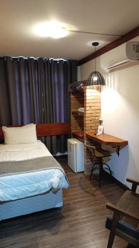 a bedroom with a bed and a desk and a table at Hotel Senador By Nobile in Quedas do Iguacu